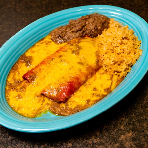 El Chaparral's enchiladas covered in melted cheese, with a side of refried beans and rice.