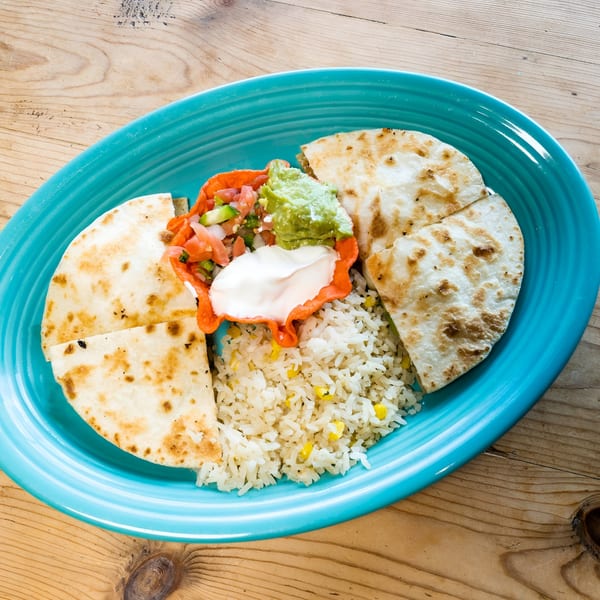 El Chaparral quesadillas, rice, guacamole, salsa, and sour cream on a blue plate.