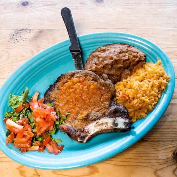 El Chaparral Mexican Restaurant's pork chop with red sauce, rice, refried beans, and salad.