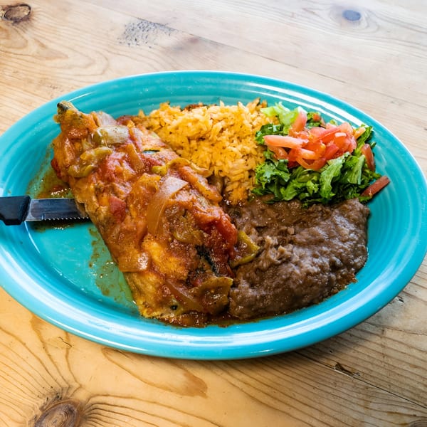 El Chaparral's Mexican dish with a knife, rice, beans, and salad on a blue plate.